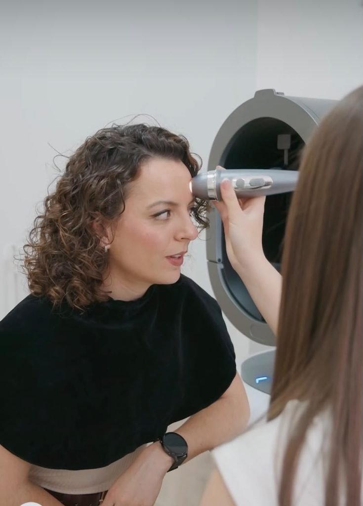 Esteticista realizando un diagnóstico facial con analizador de piel a una clienta