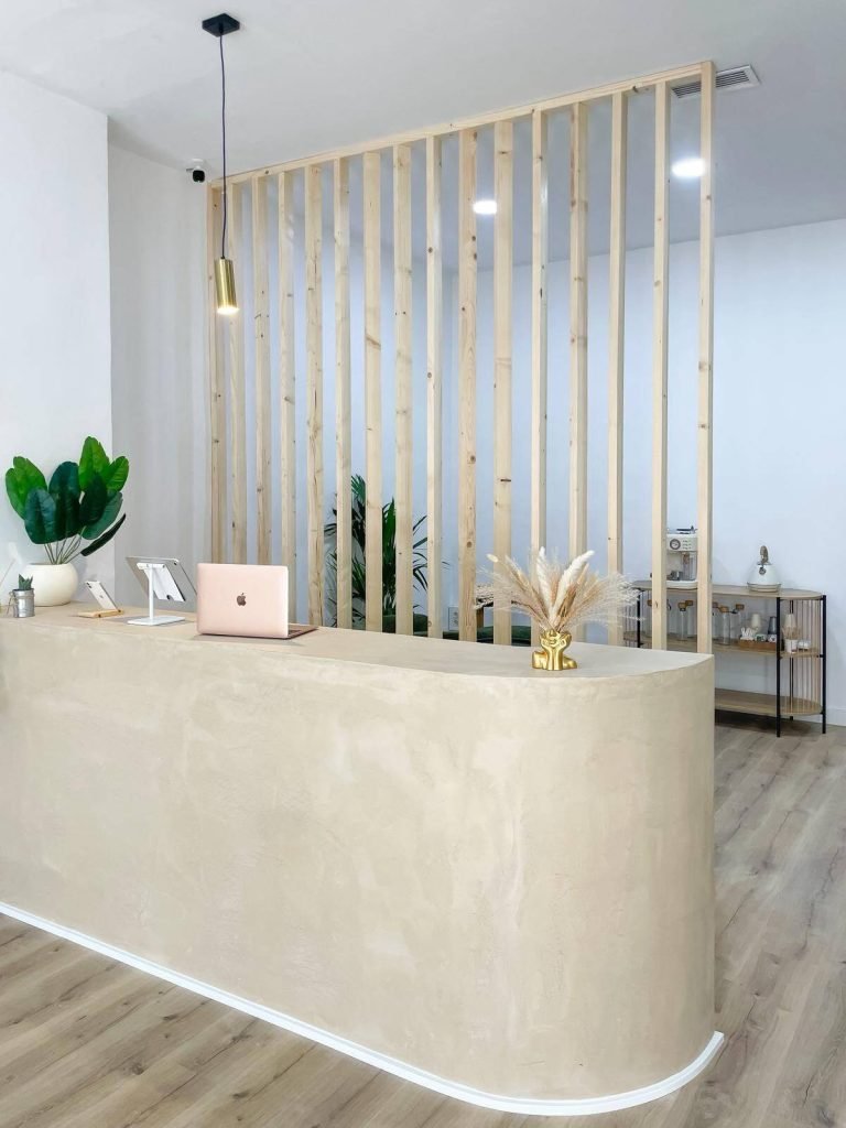 Recepción de NG Aesthetics Granada, con mostrador curvo y separador de listones de madera